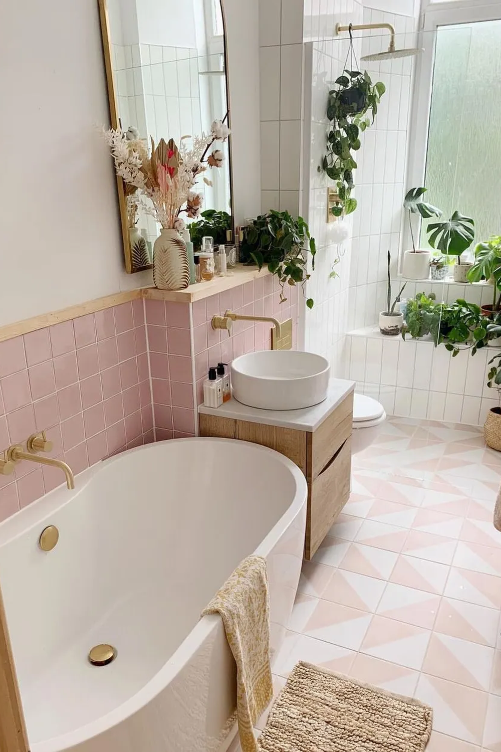 A beautifully designed vintage pink tile bathroom with modern fixtures and greenery.