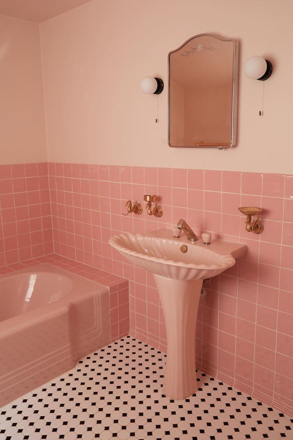 A classic vintage pink bathroom showcasing a scallop-shaped sink and elegant features.