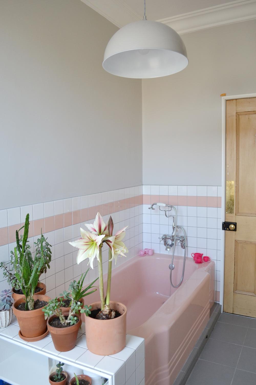 Vintage pink tile bathroom featuring elegant lighting and natural elements.
