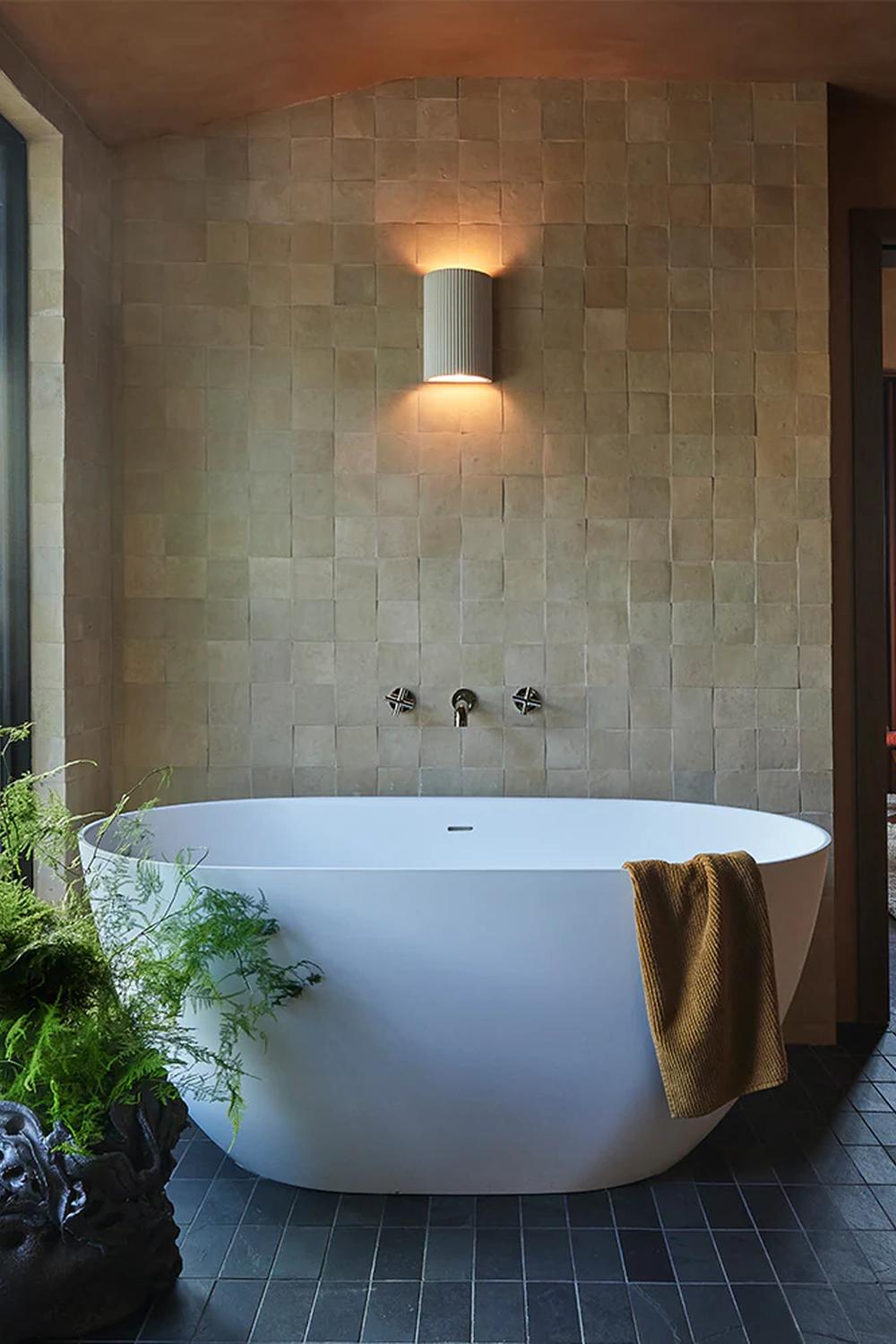Baño wabi-sabi con una bañera independiente y azulejos de piedra natural.