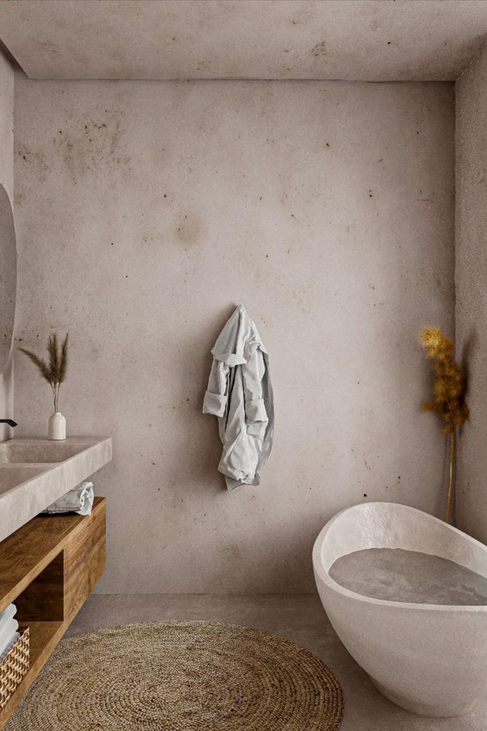 Baño minimalista con bañera escultural y decoración natural.