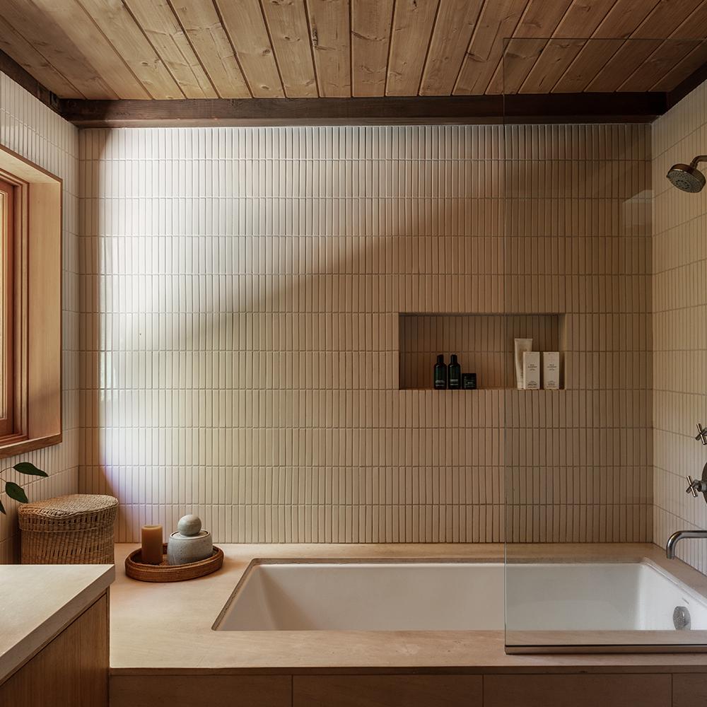 Baño wabi-sabi con bañera rectangular y diseño minimalista.