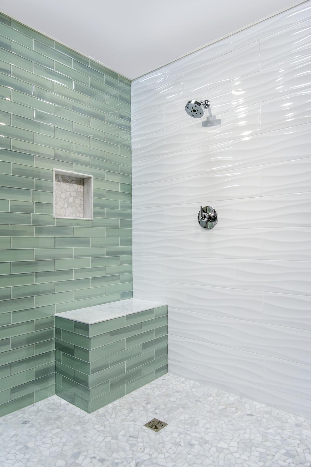 Ducha fresca y moderna con azulejos ondulados en tonos claros.