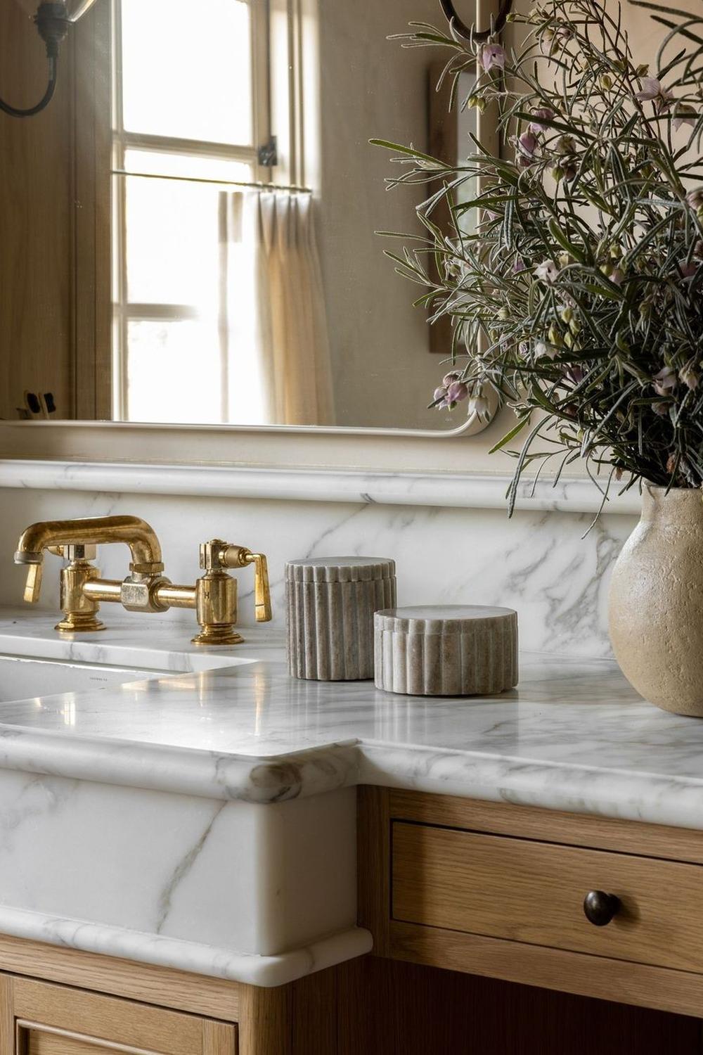 Sophisticated bathroom featuring a white marble countertop and vintage-inspired gold fixtures.