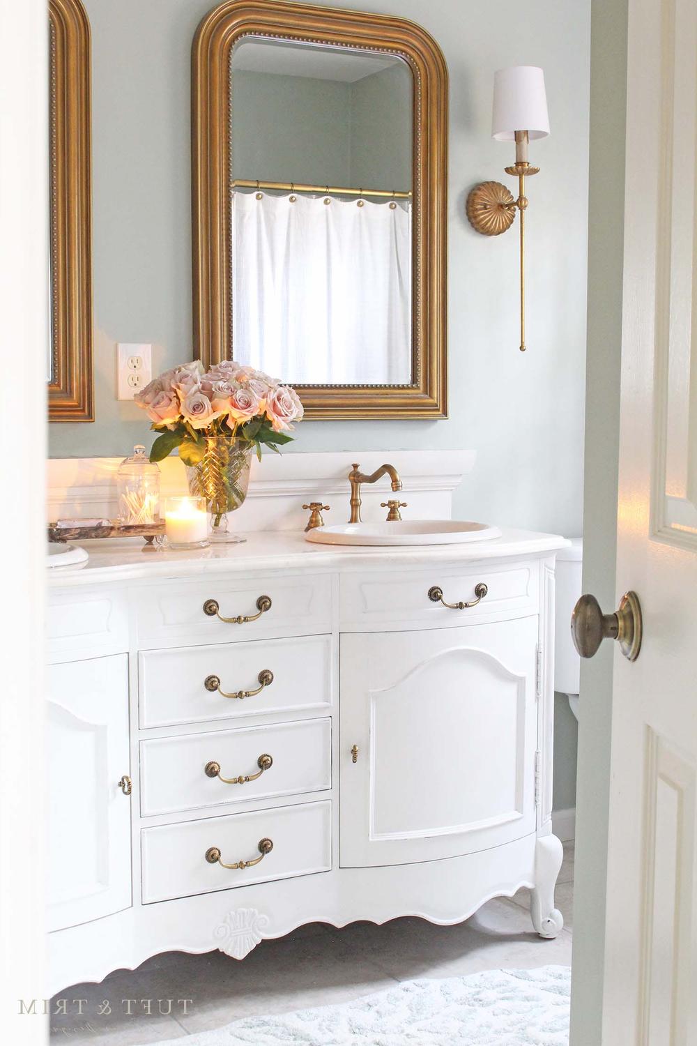 Elegant bathroom with light blue walls and gold fixtures.
