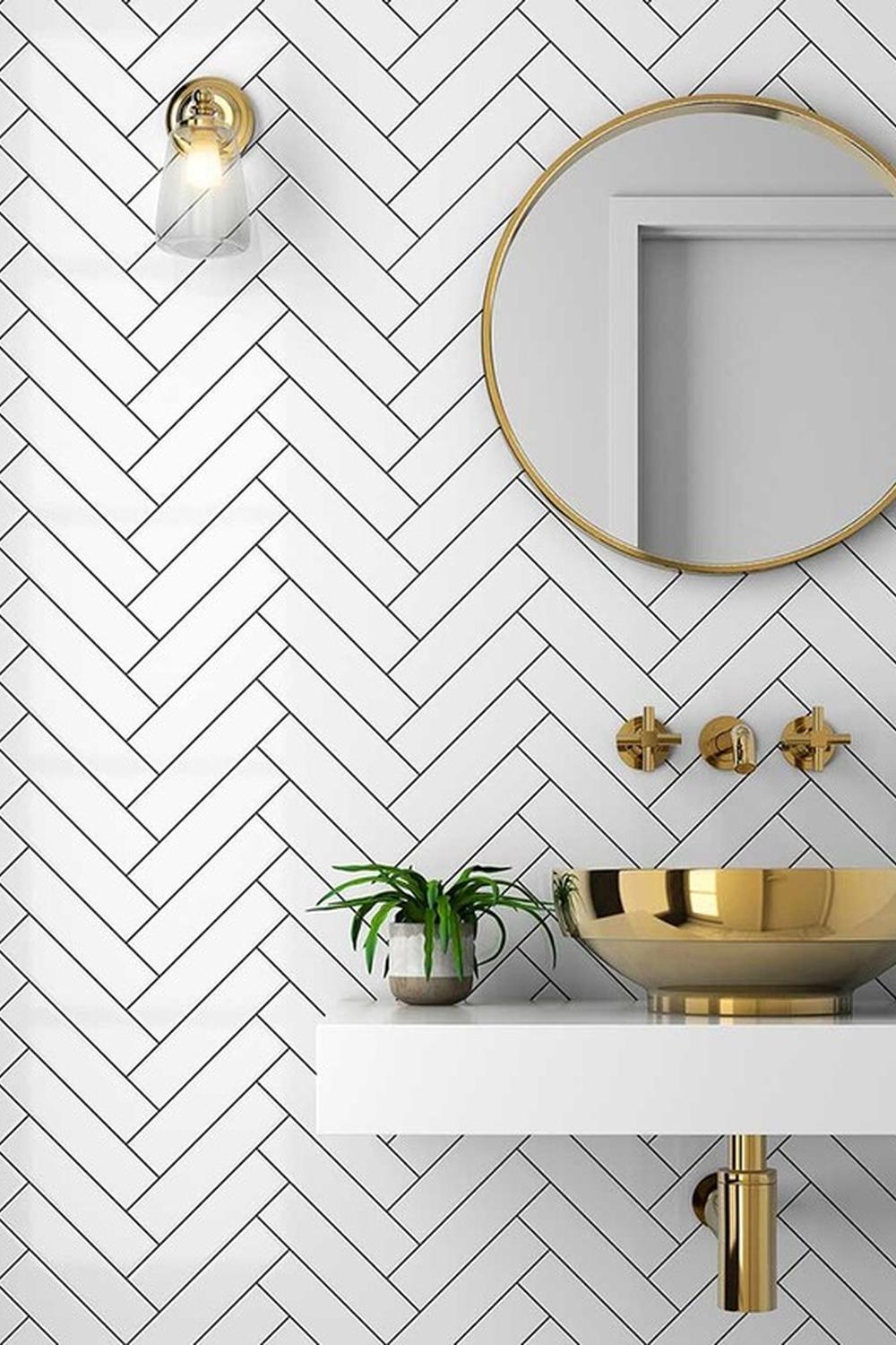 Stylish bathroom showcasing herringbone tiled wall and gold vessel sink