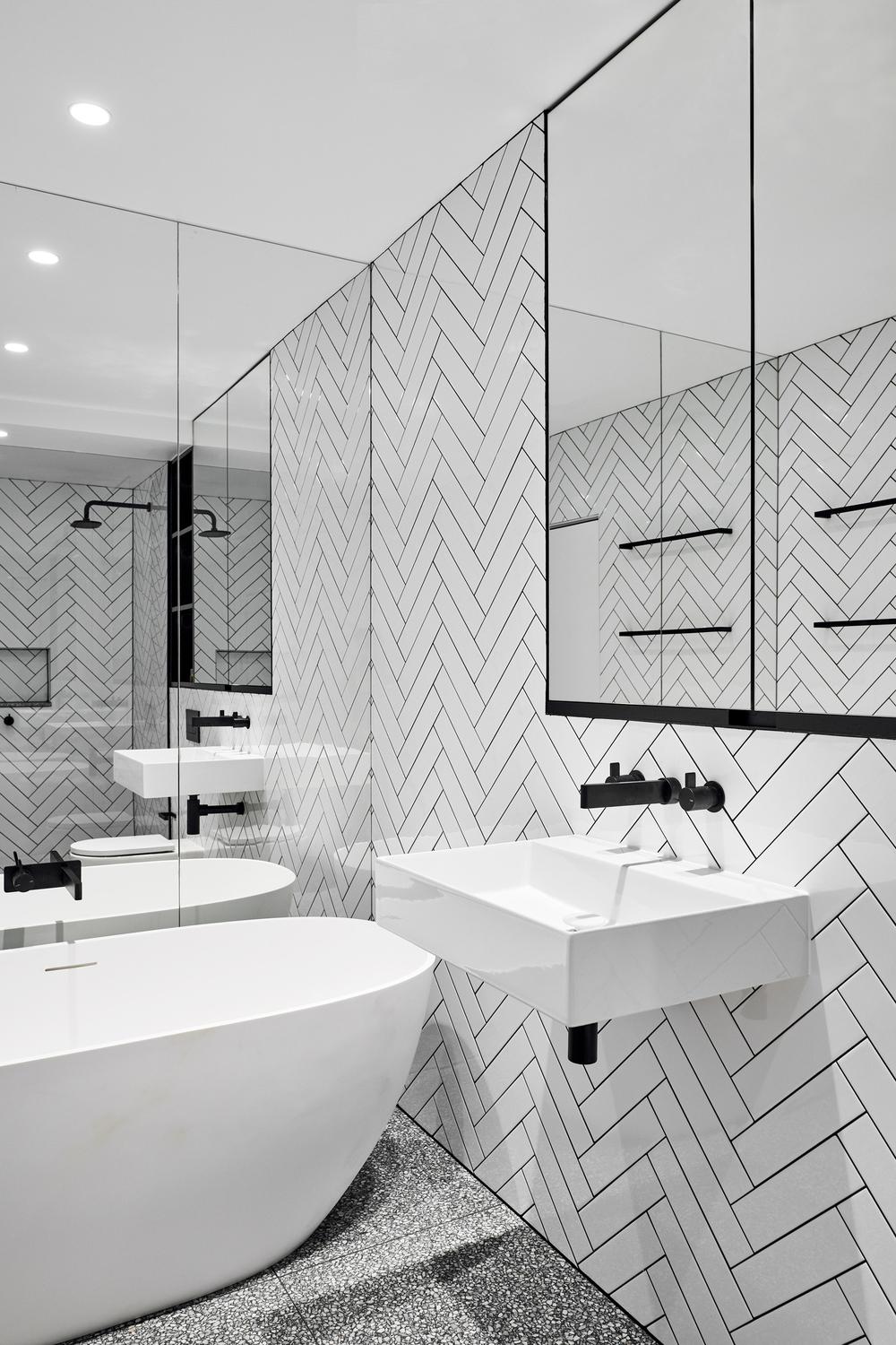 Modern bathroom with herringbone tiles and minimalistic black fixtures