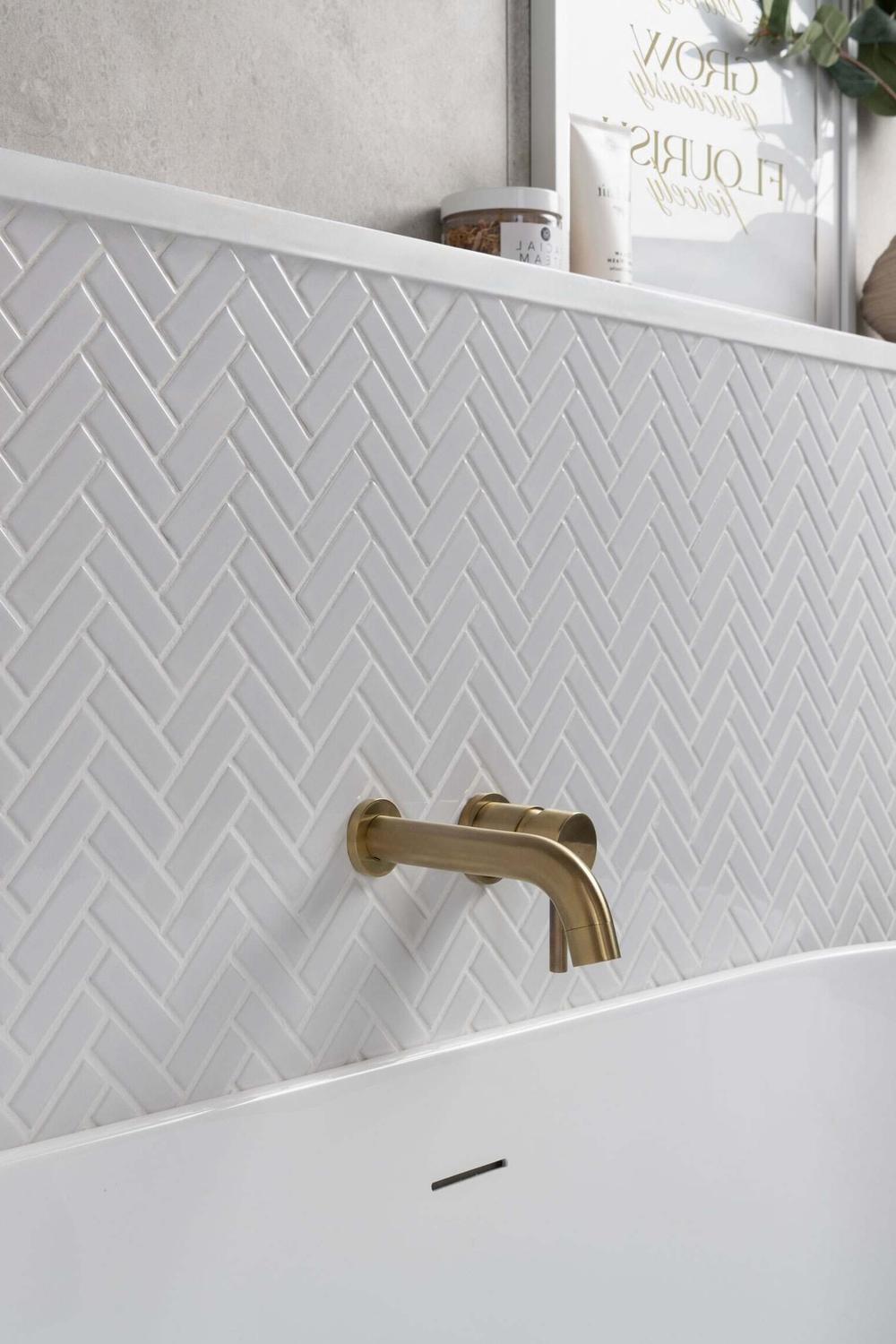 Modern bathroom with tonal contrasts between herringbone walls and a white bathtub