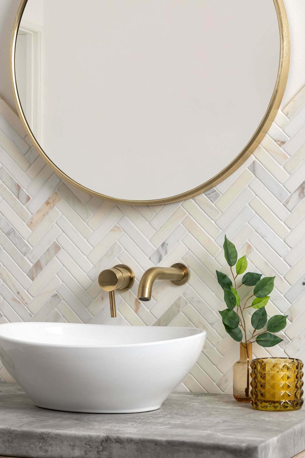 Modern bathroom with elegant herringbone tile walls and a vase of greenery