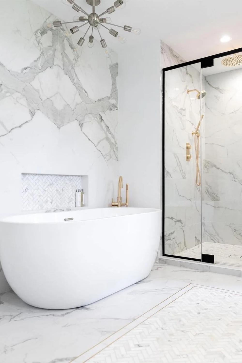 A modern bathroom featuring white marble and a chandelier for an elegant touch.