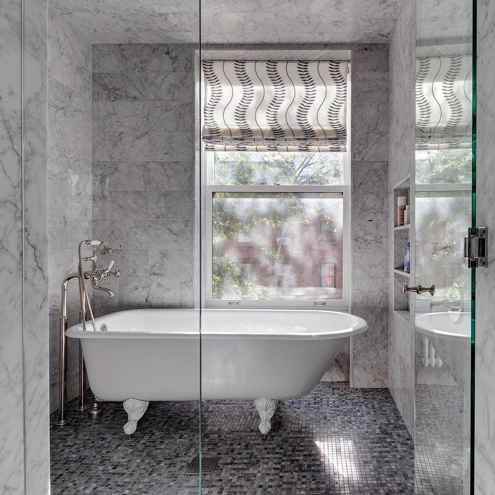 Elegant vintage-inspired bathroom featuring white marble tiles, a freestanding bathtub, and contemporary design.