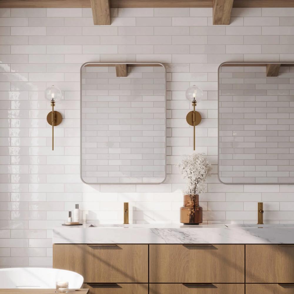Elegant modern white subway tile bathroom featuring two mirrors, wooden vanity, and gold finishes.
