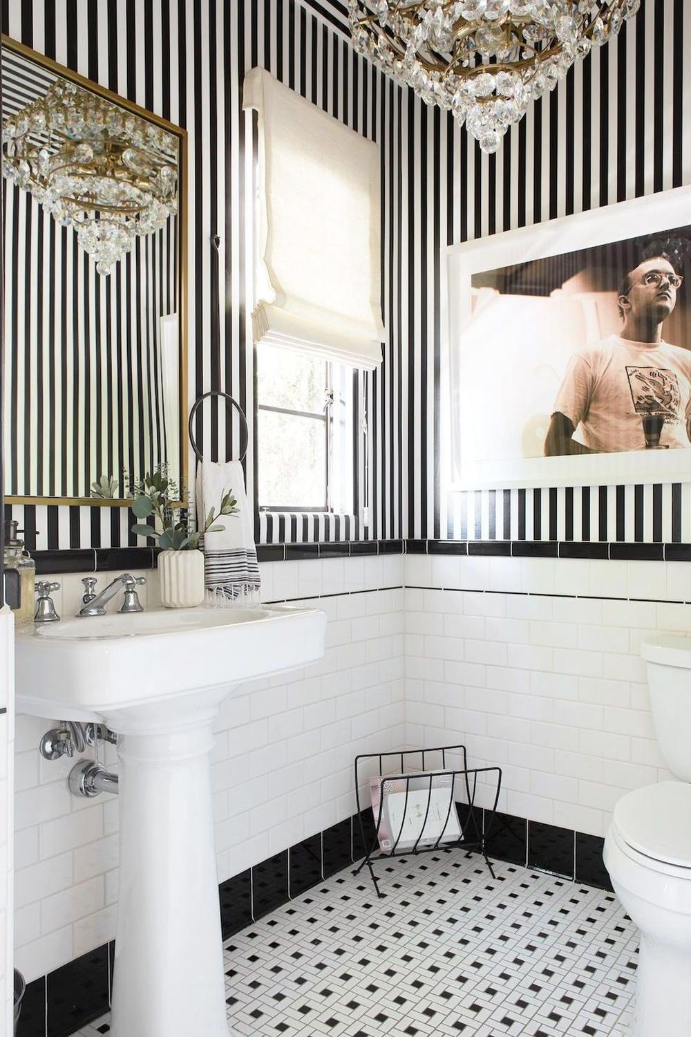 Stylish small bathroom design with black and white details, white subway tiles, and a chic chandelier.