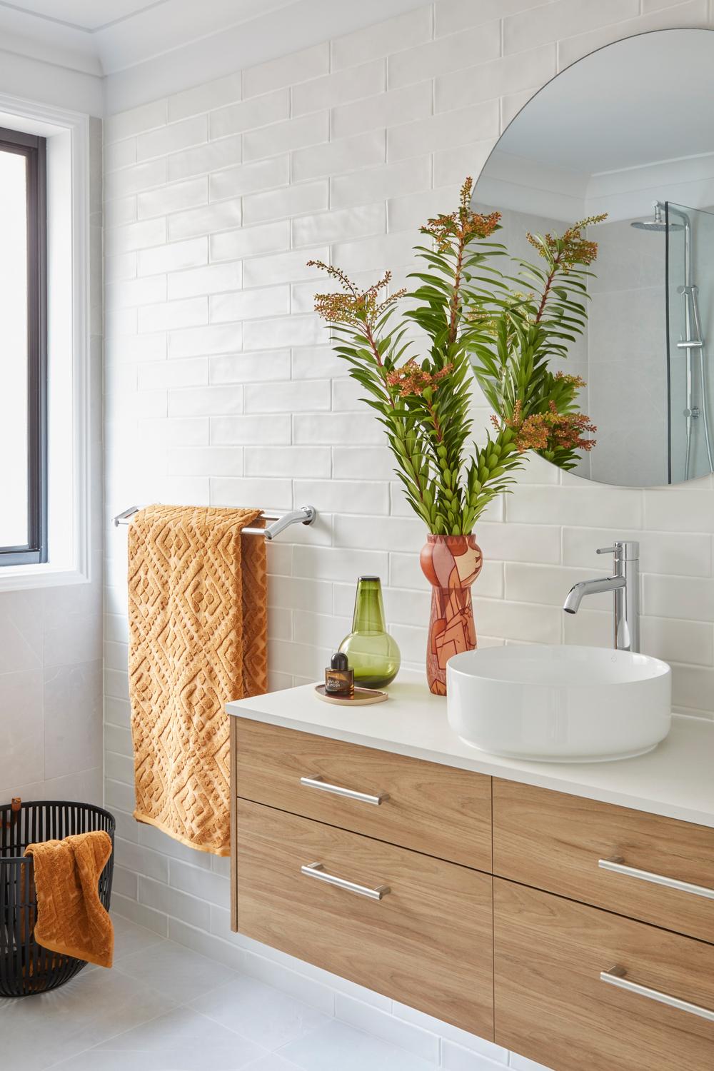 Contemporary bathroom design featuring spacious lighting, white subway tiles, and modern sink.