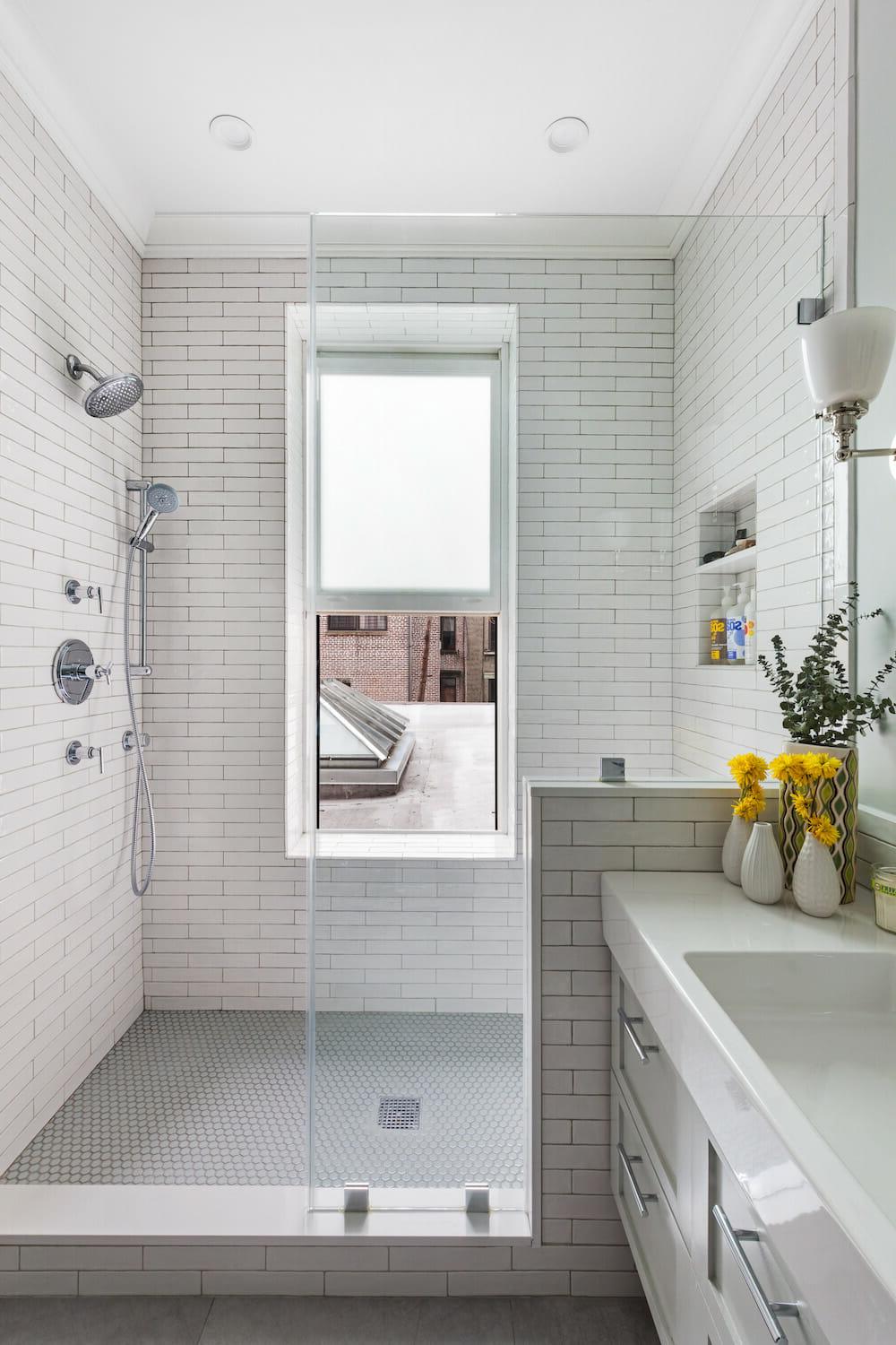 Minimalist bathroom featuring white subway tiles, elegant shower, and modern vessel sink.