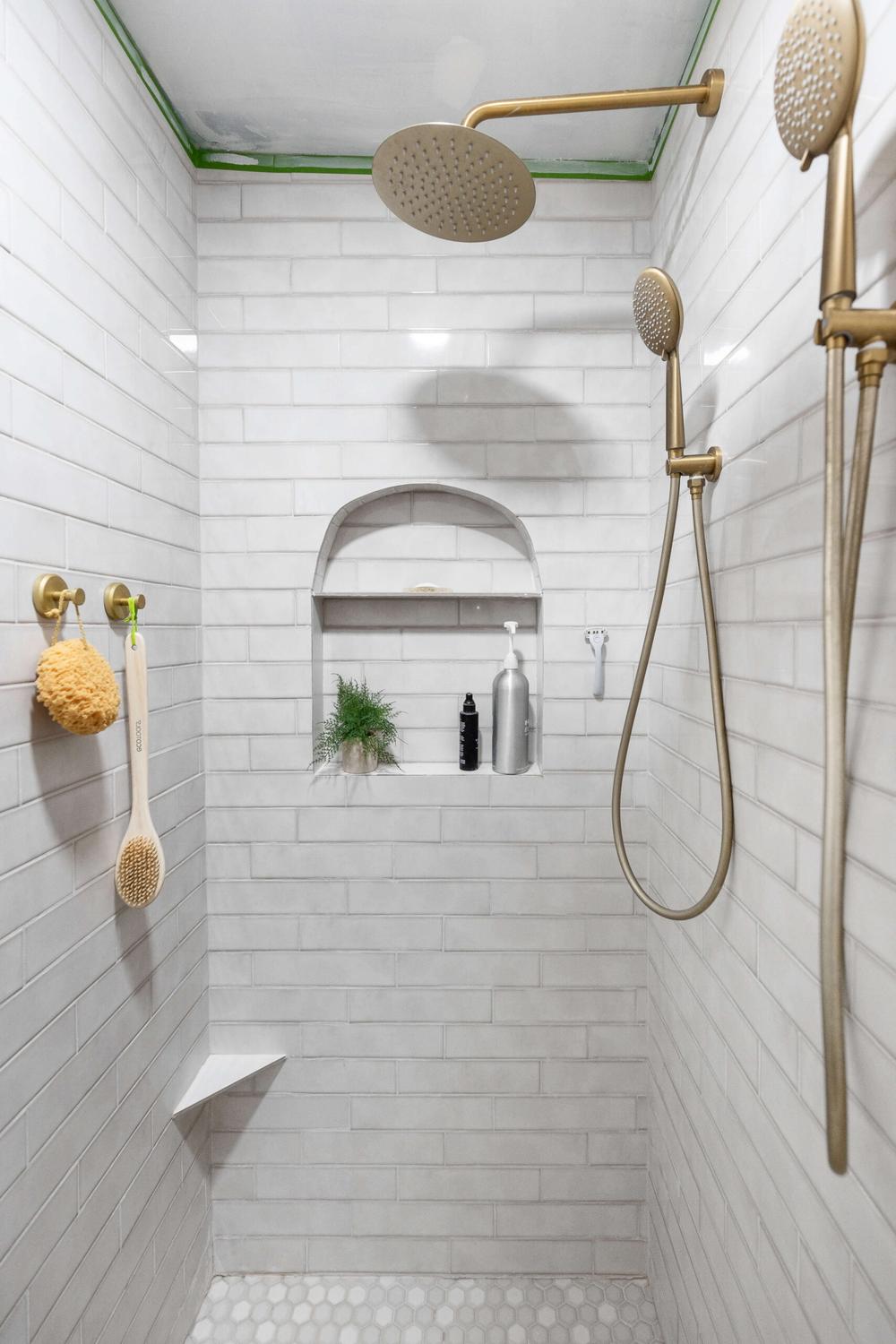 Modern shower design showcasing white subway tiles, luxurious fixtures, and niche shelving.