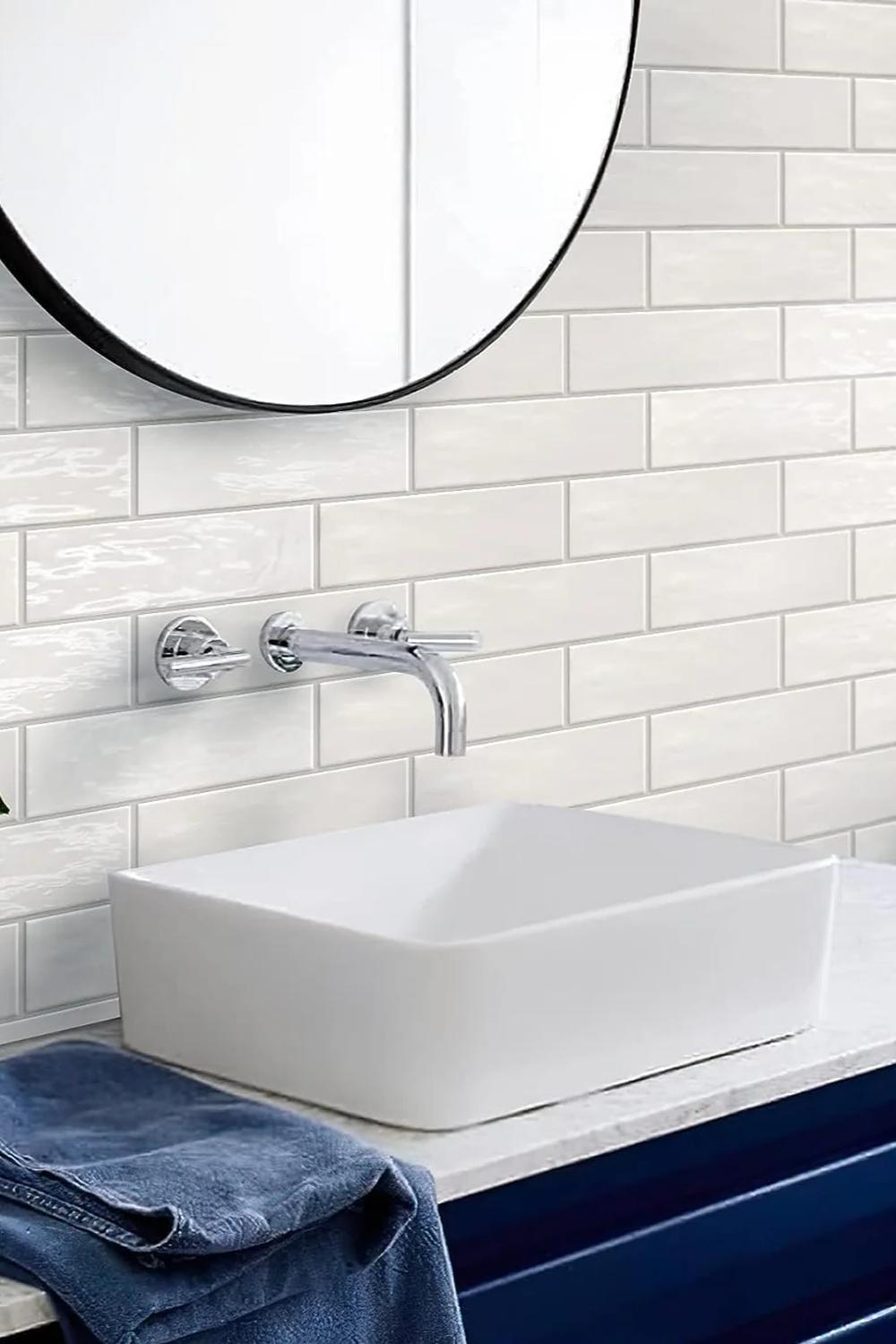 Bold and bright bathroom showcasing white subway tiles, round mirror, and stylish cabinetry.