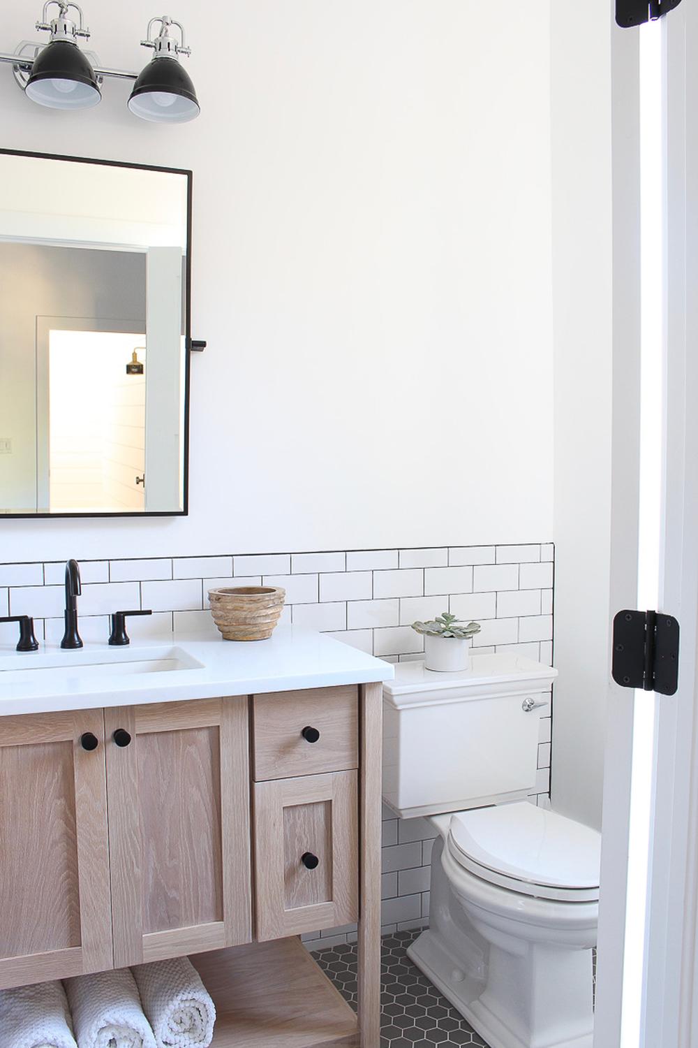 Sleek bathroom design featuring white subway tiles, dark hexagonal flooring, and rustic accents.