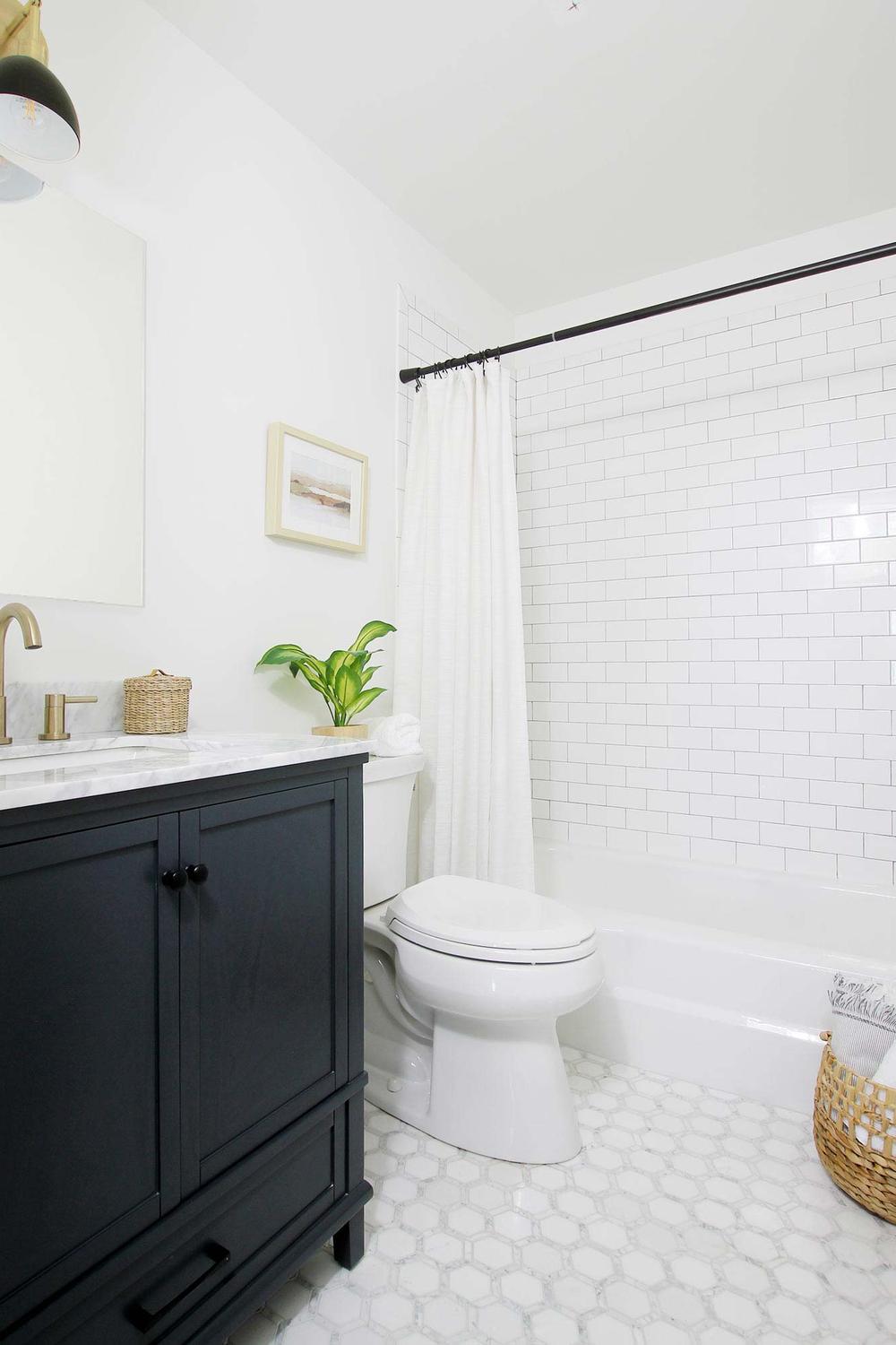 Stylish bathroom with black vanity, white marble countertop, and hexagonal white tiles