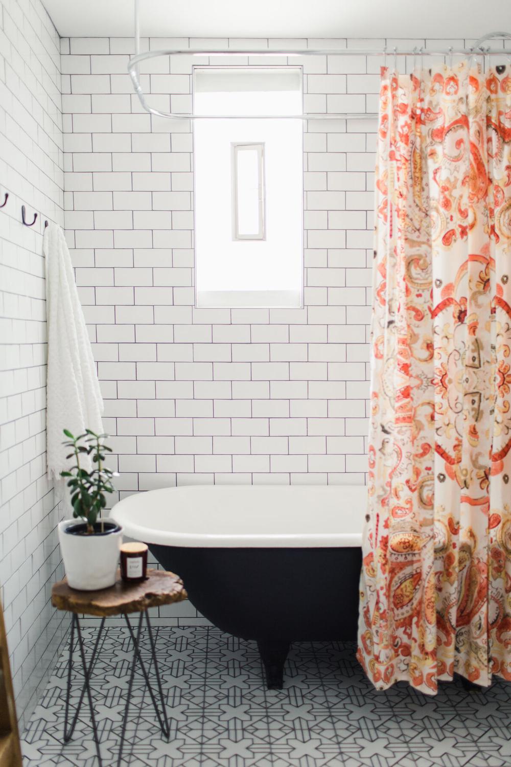 Vintage-style freestanding tub in a modern bathroom with intricate gray and white tiled floor