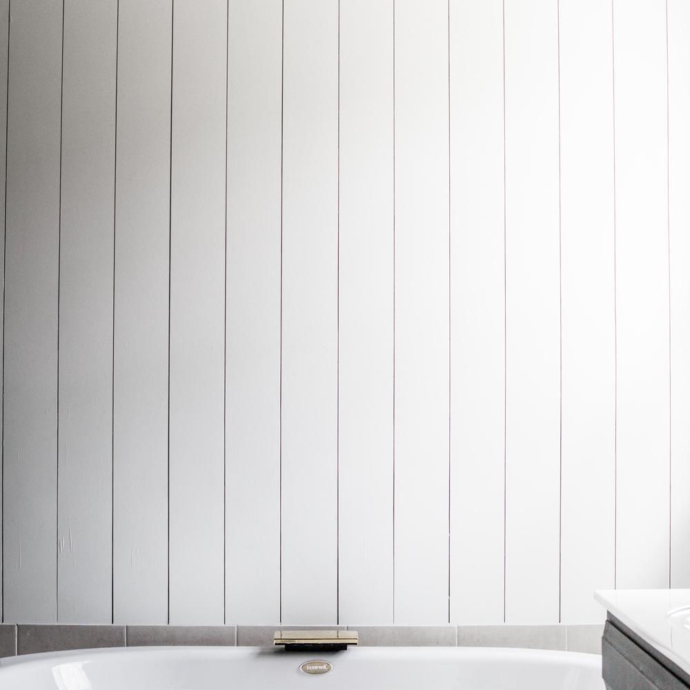 Bright and airy bathroom showcasing vertical shiplap criteria with light fixtures and bathtub.
