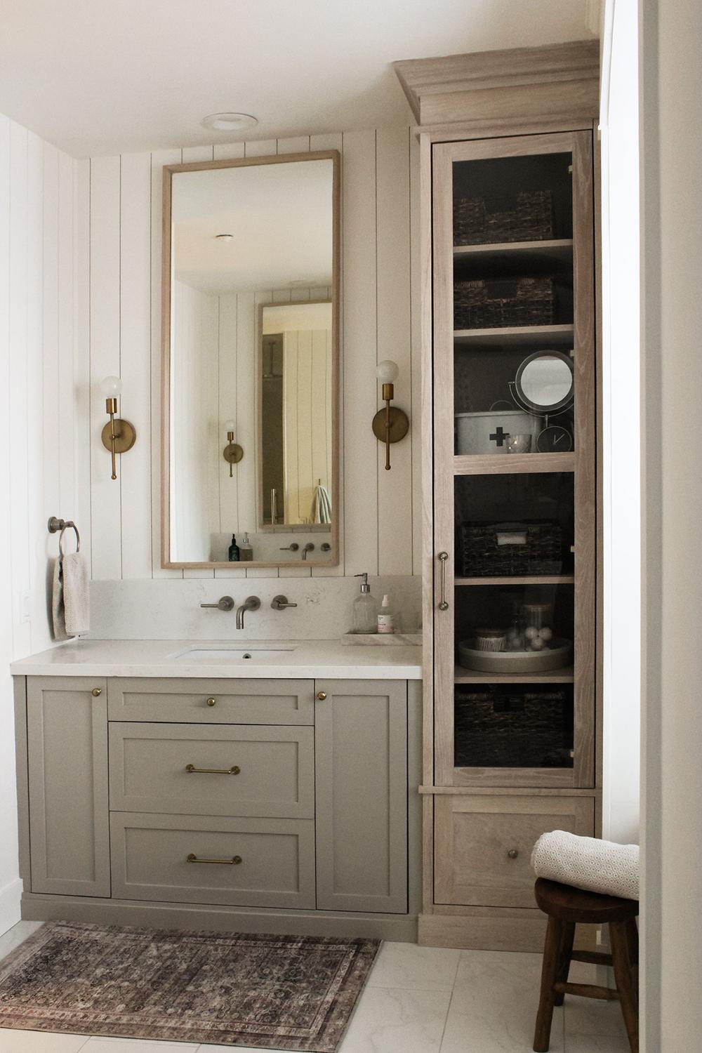 Coastal-style bathroom featuring white vertical shiplap, gray vanity, and natural elements.