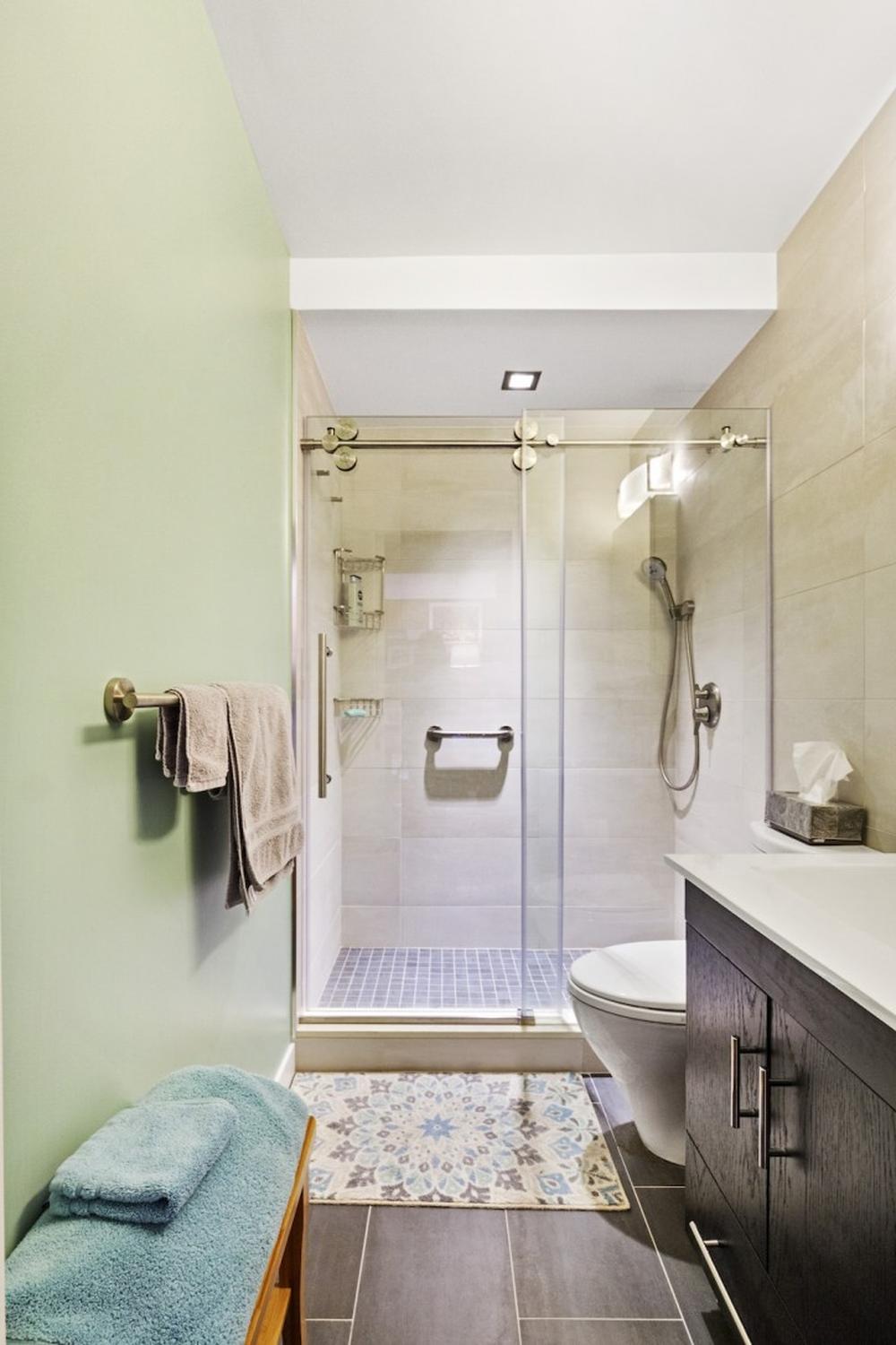 Small windowless bathroom with soothing light green walls and modern fixtures