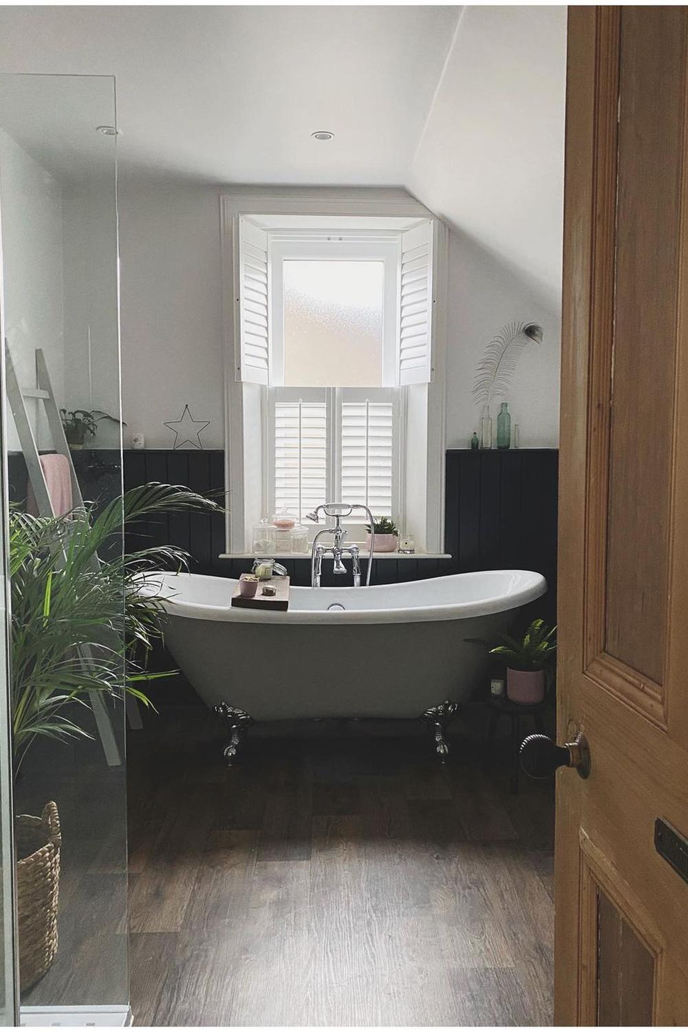 Charming bathroom with dark wood flooring, freestanding bathtub, and natural light.