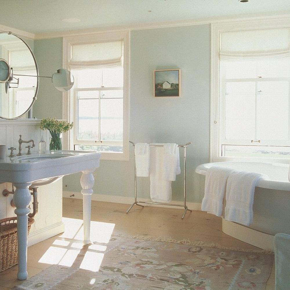 Elegant bathroom with light blue walls, wooden flooring, and vintage sink.