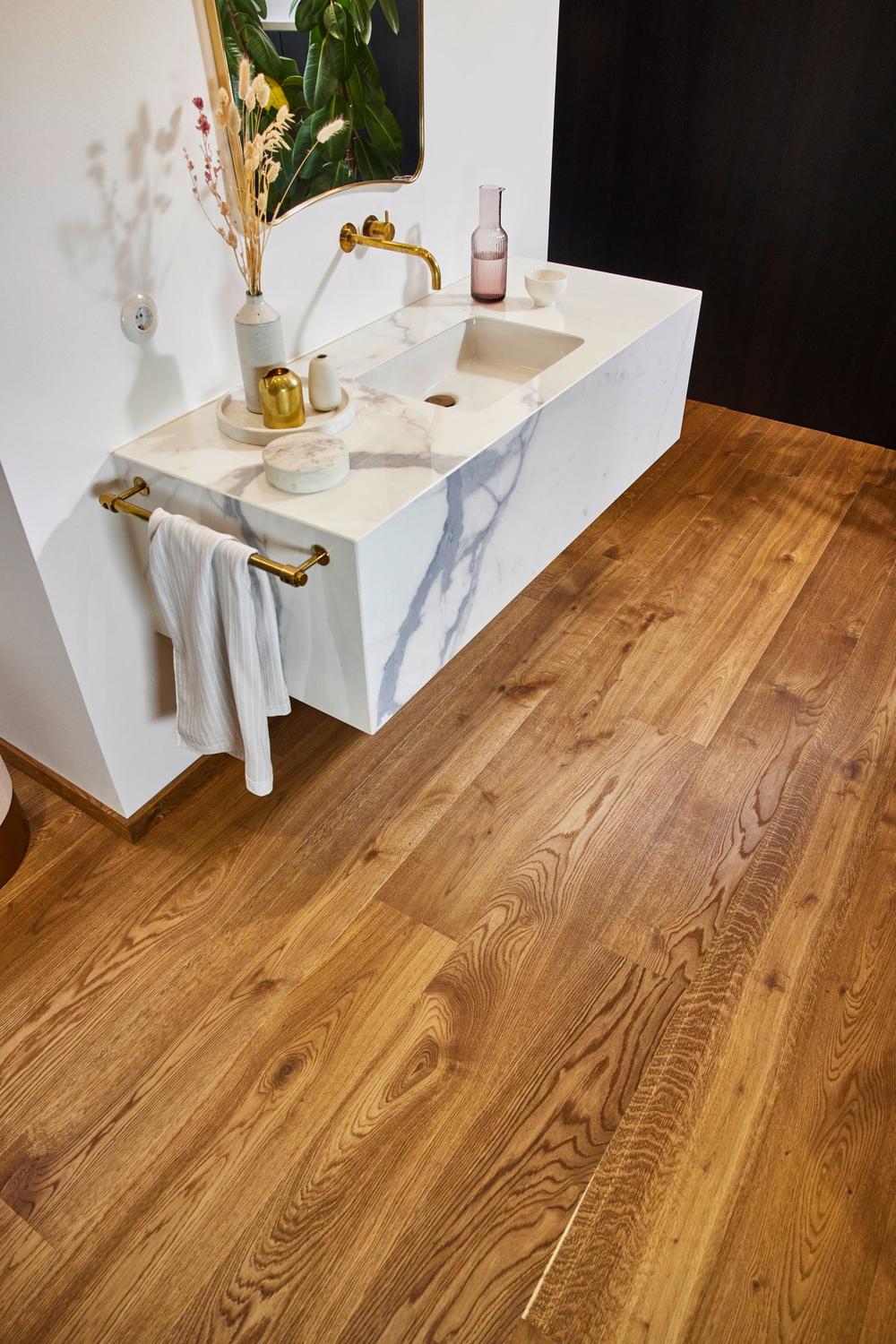Stylish bathroom showcasing rich wood tones, modern marble vanity, and gold accents.