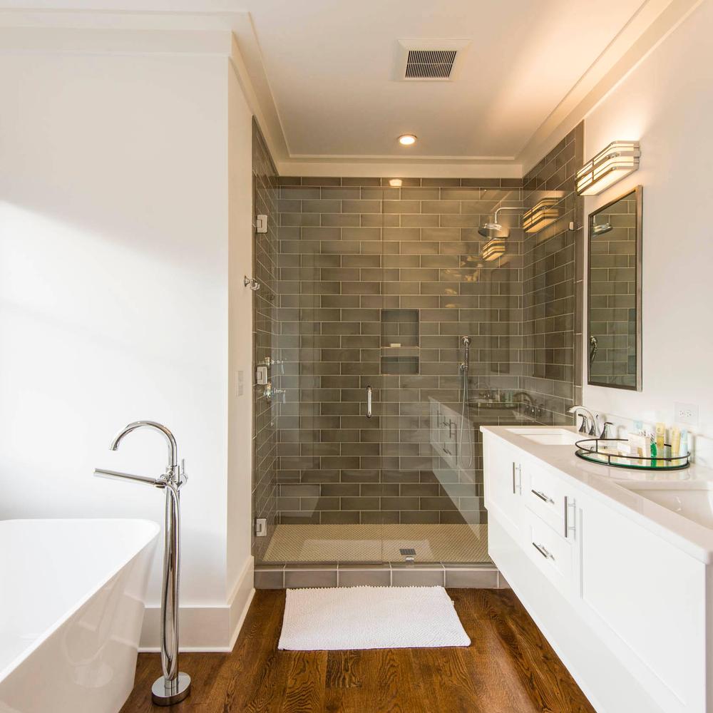 Inviting modern bathroom with wooden flooring, glass shower, and freestanding tub.