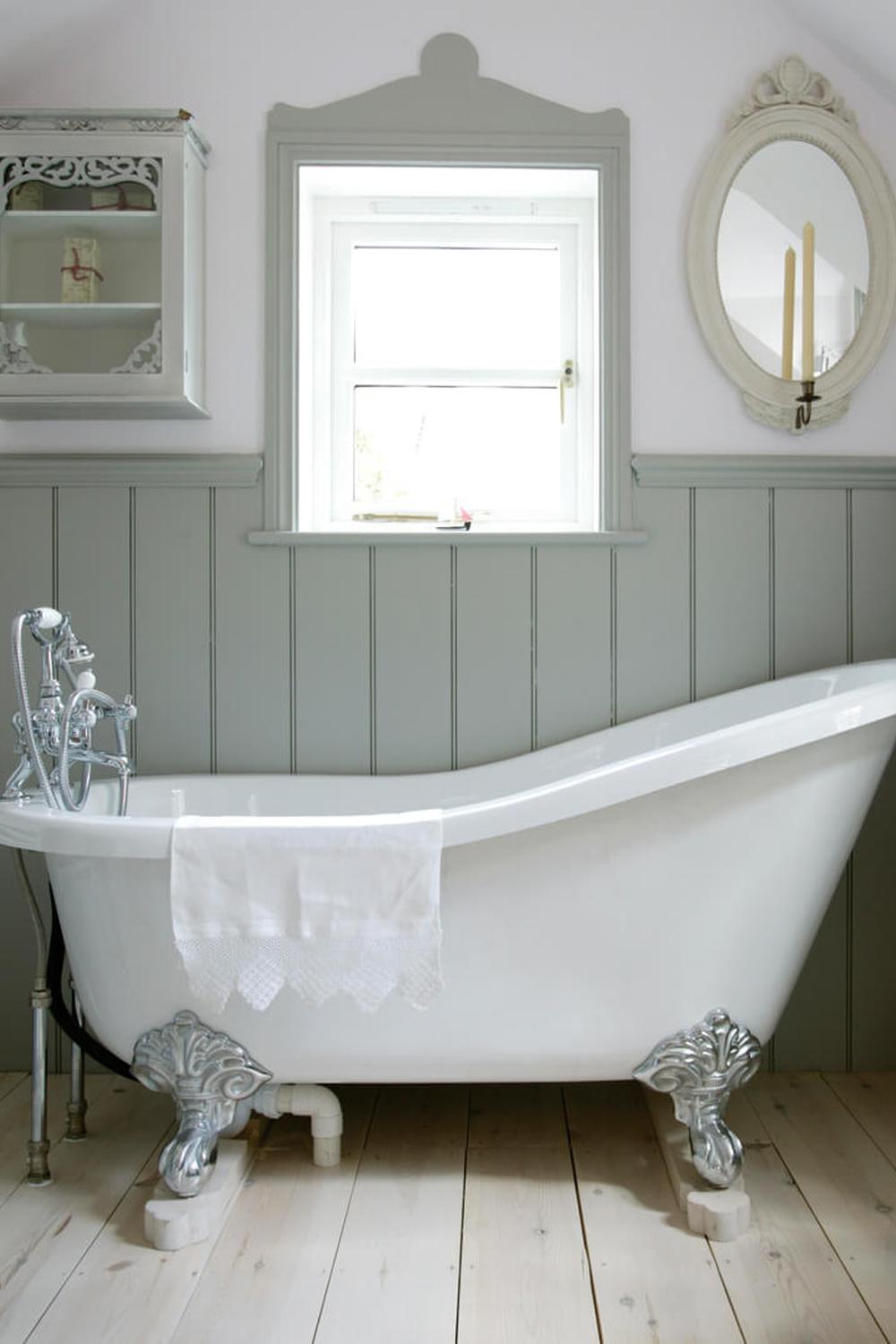 Baño elegante con bañera de patas de garra y paneles de madera