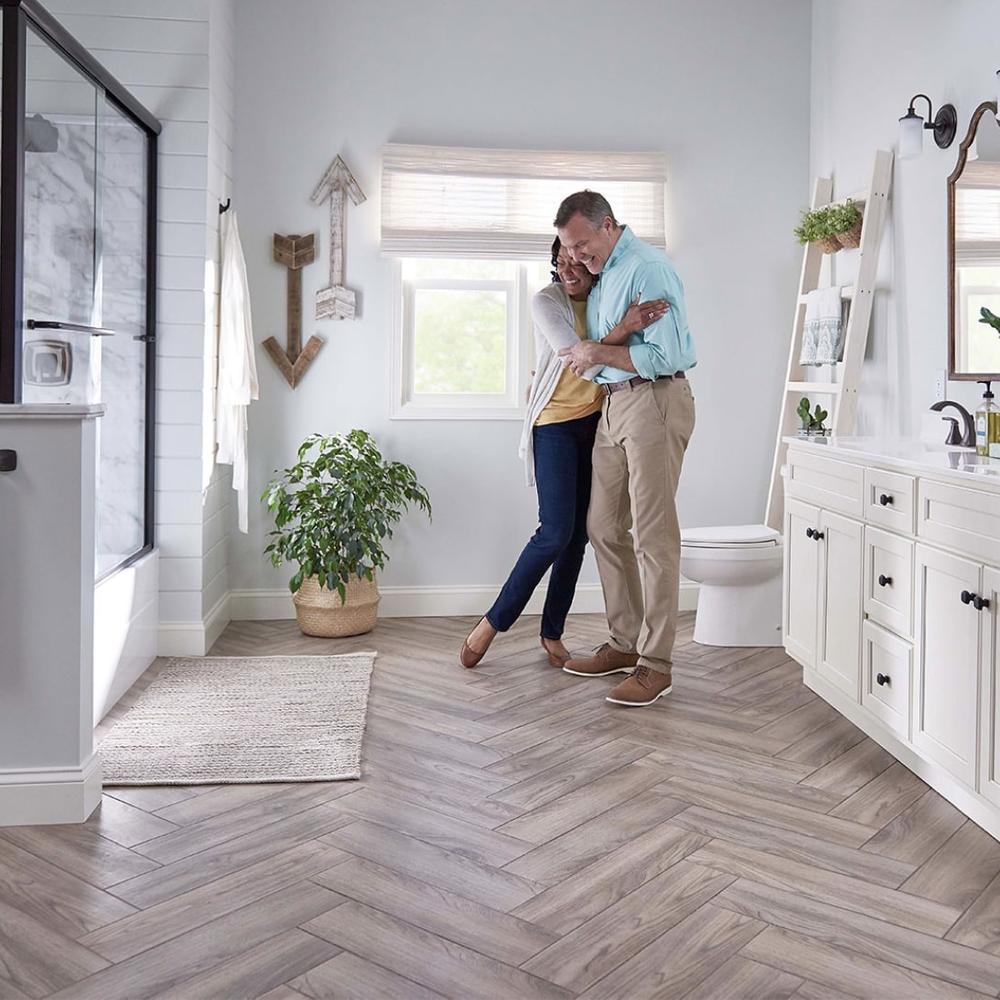 Stylish bathroom with herringbone wood tile floor, modern fixtures, and a happy couple enjoying the space.