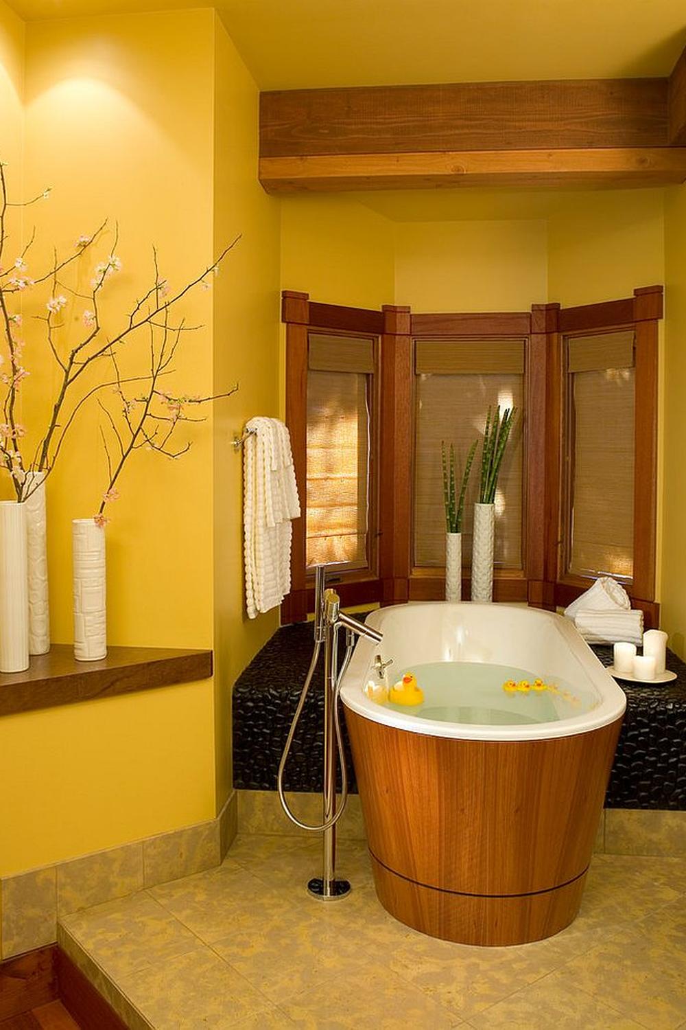 A modern yellow bathroom showcasing a chic freestanding bathtub and lush plants for a relaxing atmosphere.
