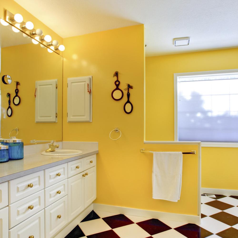 A bright yellow bathroom featuring black and white decor elements, creating a stylish and cheerful ambiance.