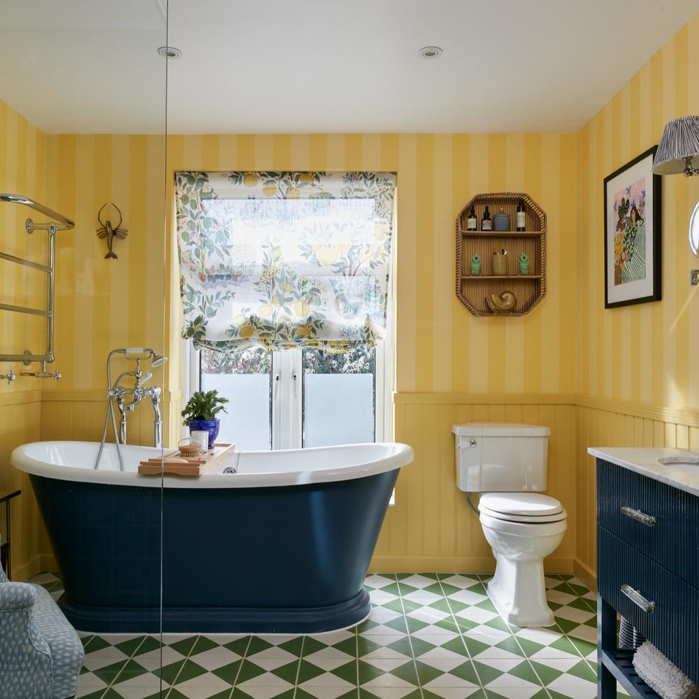 A modern yellow bathroom featuring a freestanding tub and green and white tiled flooring for a stylish look.