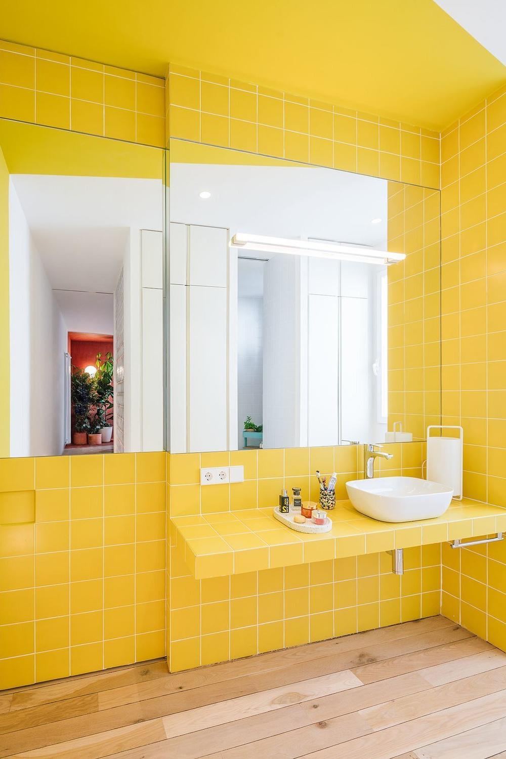 A contemporary yellow bathroom featuring glossy tiles and a modern vibe, radiating brightness and cheer.