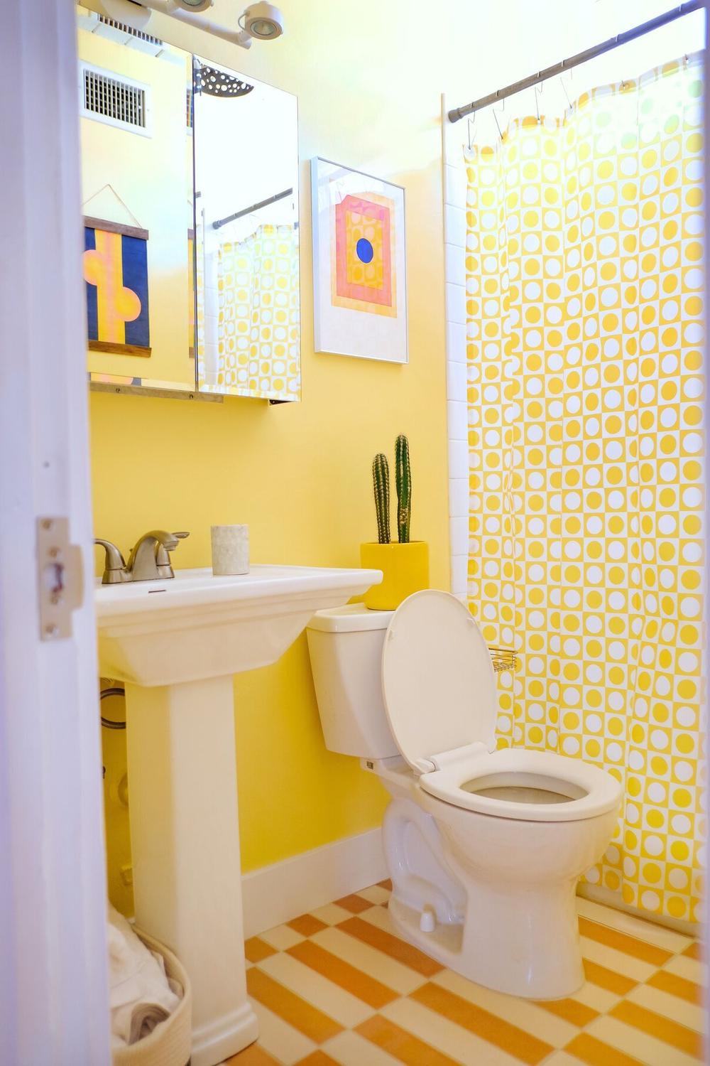 Playful bathroom with yellow tiles and patterned shower curtain